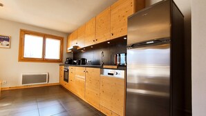 A modern kitchen with wooden cabinets, stainless steel appliances, and a large window. - Bright T3 apartment for 4-6 people with WIFI and parking in Samoëns (Samoëns)