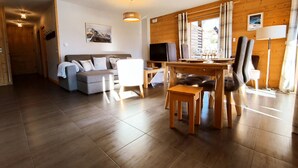 A modern living room with a sofa, TV, dining table, and chairs. - Bright T3 apartment for 4-6 people with WIFI and parking in Samoëns (Samoëns)
