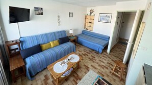 Un salon confortable avec un canapé, une petite table, un téléviseur et une bibliothèque.