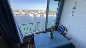 Un balcon avec une table et des chaises, une vue sur une marina remplie de bateaux et une décoration murale.