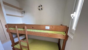Un lit superposé avec une échelle, une étagère au-dessus et un gilet de sauvetage accroché au mur.
