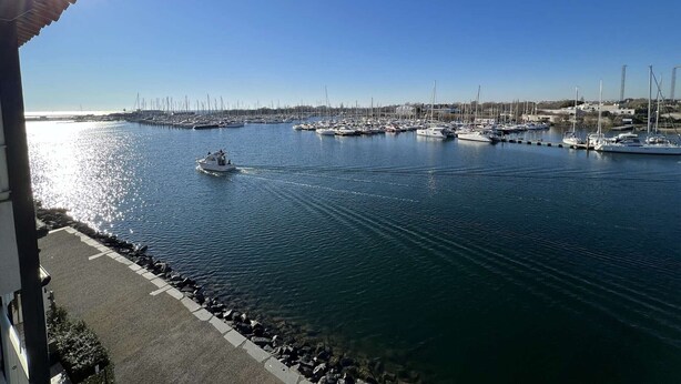 Un port de plaisance avec des bateaux amarrés, un ciel dégagé et une journée ensoleillée.