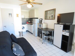 A compact living space with a kitchenette, a dining area, and a television.