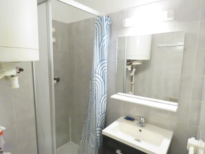 A bathroom with a shower, a sink, and a mirror.