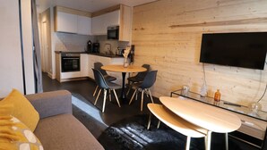 A modern living space with a kitchen, dining area, and a flat-screen TV mounted on the wall. - Renovated bright studio with balcony - Close to slopes (Tignes)