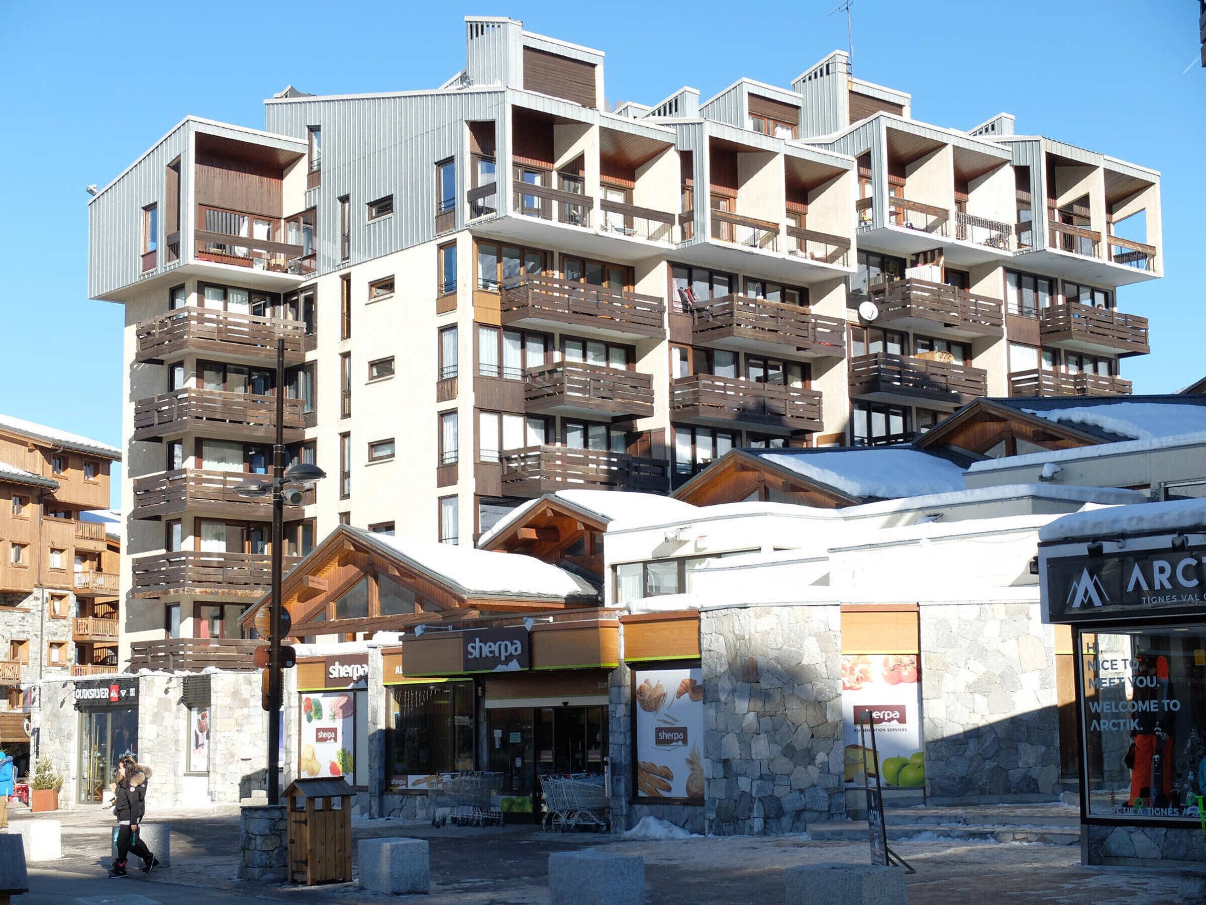 Et hotel med flere etager og altaner, et skisportssteds skilt, og en butik med Sherpa-udstyr.