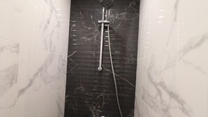 A bathroom with a shower, marble walls, and a tiled floor. - Renovated bright studio with balcony - Close to slopes (Tignes)