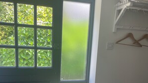 A room with a green-framed window, a white basket, and a wooden hanger on the wall.