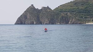 Un kayak sur une étendue d’eau calme, avec une côte rocheuse et, au loin, une structure qui ressemble à un château.