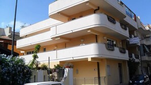 Un immeuble à plusieurs étages doté de balcons, d’une entrée bien visible et d’une enseigne indiquant qu’il s’agit d’un hôtel.