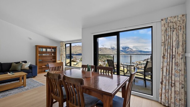 Un salon moderne avec un coin repas, de grandes fenêtres, une bibliothèque et une vue sur les montagnes.