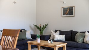 Un salon avec un canapé bleu foncé, une table basse en bois et une plante en pot.