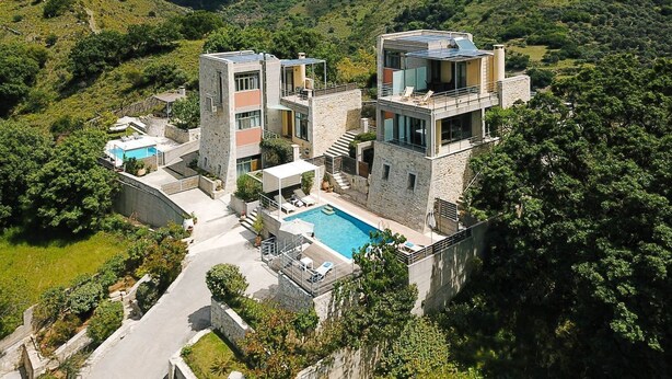 Una villa moderna con piscina, rodeada de exuberante vegetación y montañas.