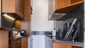 A compact kitchen with wooden cabinets, a stainless steel refrigerator, and a coffee machine. - Phos, an eclectic suite with stunning Acropolis view.<br> (Athina)