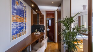 A modern interior with a wooden bench, a large potted plant, and a kitchen area with cabinets and a countertop. - Phos, an eclectic suite with stunning Acropolis view.<br> (Athina)