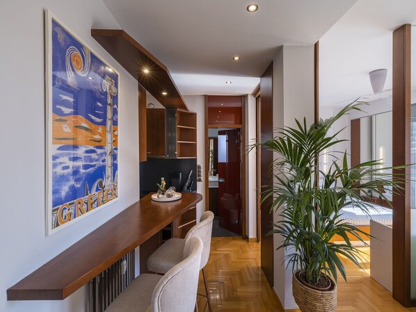 A modern interior with a wooden bench, a large potted plant, and a kitchen area with cabinets and a countertop. - Phos, an eclectic suite with stunning Acropolis view.<br> (Athina)