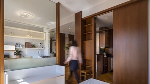 A modern bedroom with a large bed, a walk-in closet, and a kitchen area visible through an open door. - Phos, an eclectic suite with stunning Acropolis view.<br> (Athina)