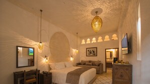 Une chambre spacieuse avec un grand lit, un bureau, une télévision et des appliques murales décoratives.