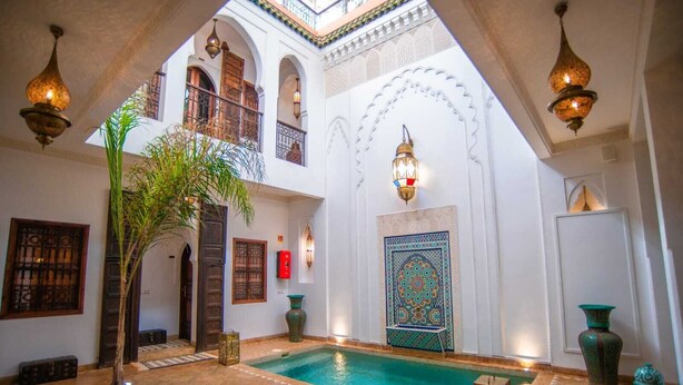Une cour avec une piscine, des balcons en arc de cercle, une décoration traditionnelle et des lampes suspendues.