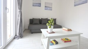 A modern living room with a grey sofa, a white coffee table with books, and a potted plant. - GuestHost - Bright & Central Apartment 5 min from the station (Salerno)
