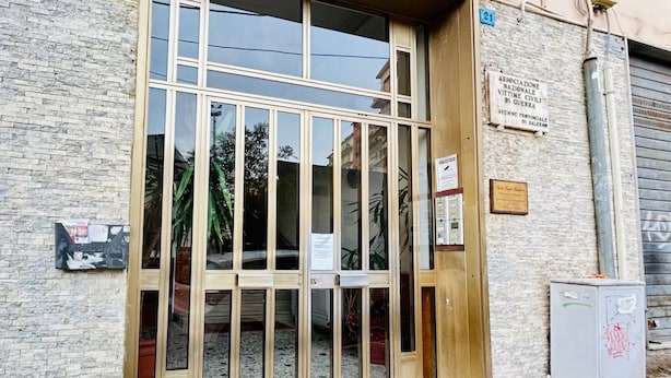 A building entrance with a glass door, a sign on the wall, and a utility box. - GuestHost - Bright & Central Apartment 5 min from the station (Salerno)
