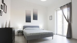 A bedroom with a bed, a dresser, a nightstand, and a window with curtains. - GuestHost - Bright & Central Apartment 5 min from the station (Salerno)