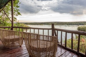 A wooden deck with wicker chairs overlooking a river.