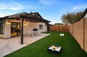 Moderni patio, jossa on pergola, keinonurmi ja pöytätennispöytä.