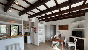 Eine geräumige Küche mit Essbereich, Holzbalken und einem großen Fenster.