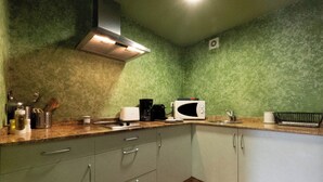 A kitchen with green textured walls, a stainless steel range hood, a microwave, and a coffee maker on the counter.