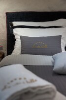 Uma cama bem arrumada com um travesseiro acolchoado cinza com a inscrição "La vita è bella" e um travesseiro decorativo com estrelas.