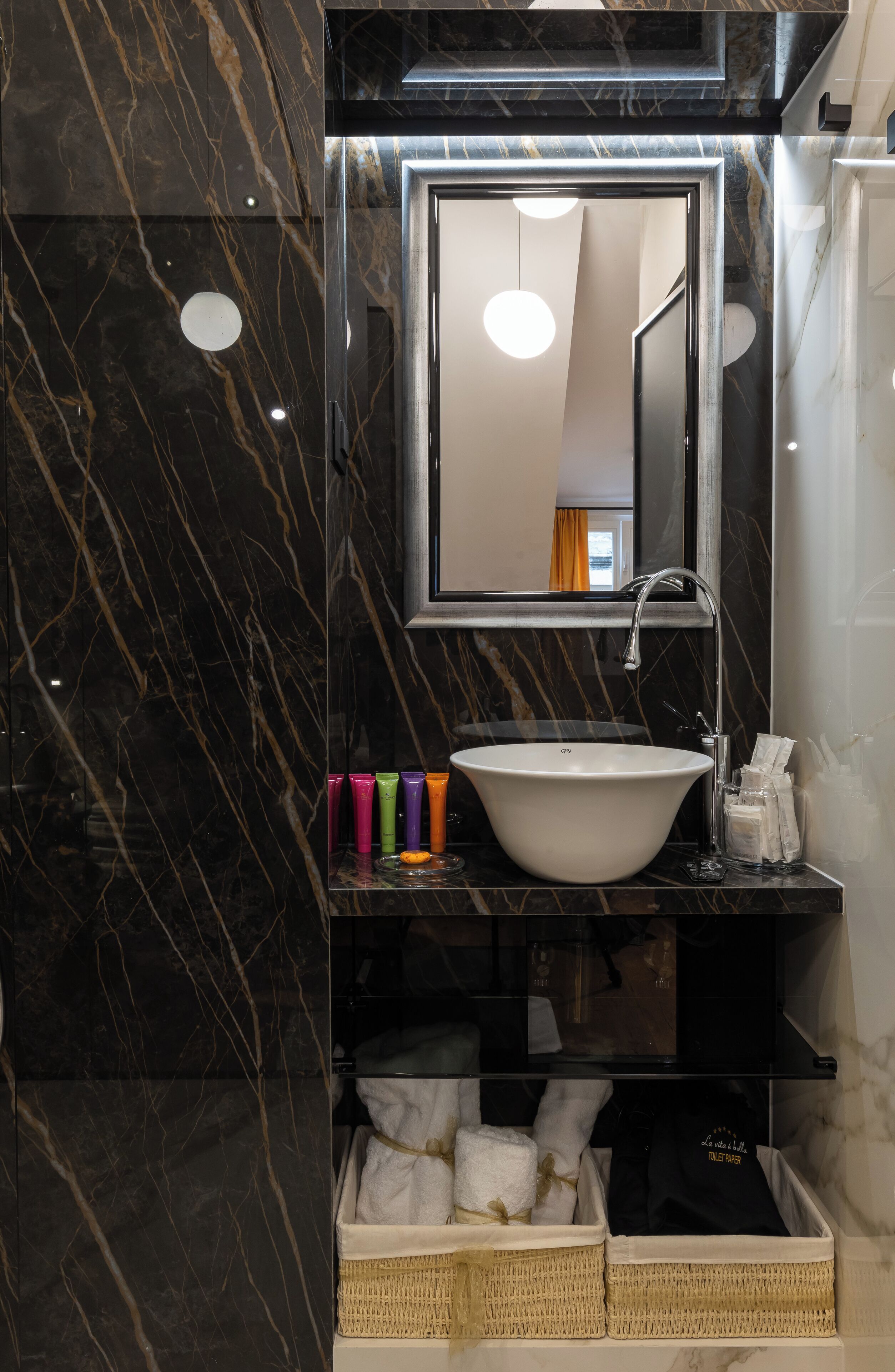 A bathroom with a marble sink, a mirror, and a shelf with toiletries.