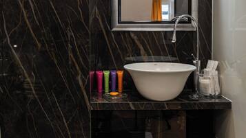 A bathroom with a marble sink, a mirror, and a shelf with toiletries.