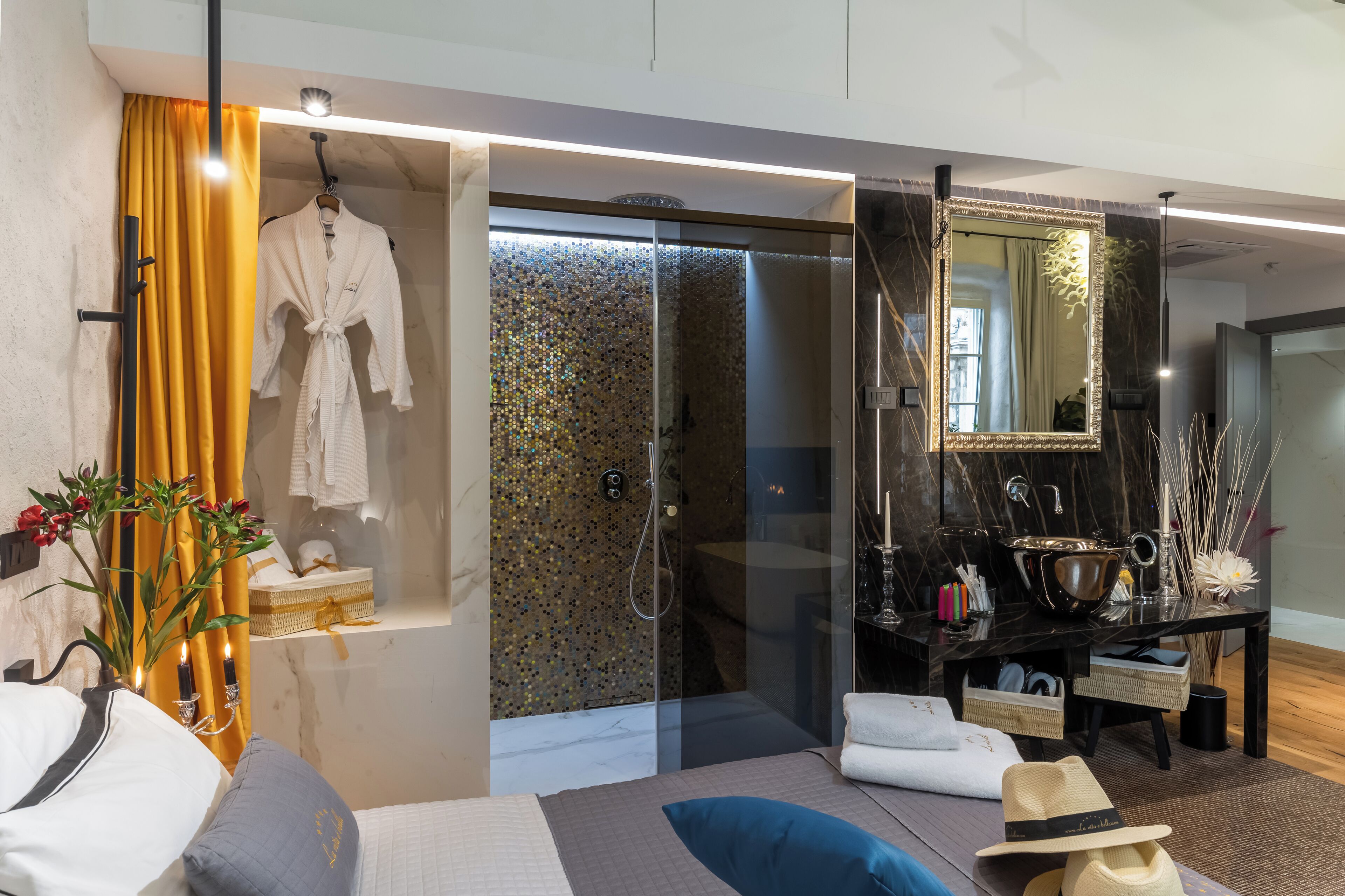 A modern bathroom with a glass-enclosed shower, a vanity with a large mirror, and a robe hanging on the wall.