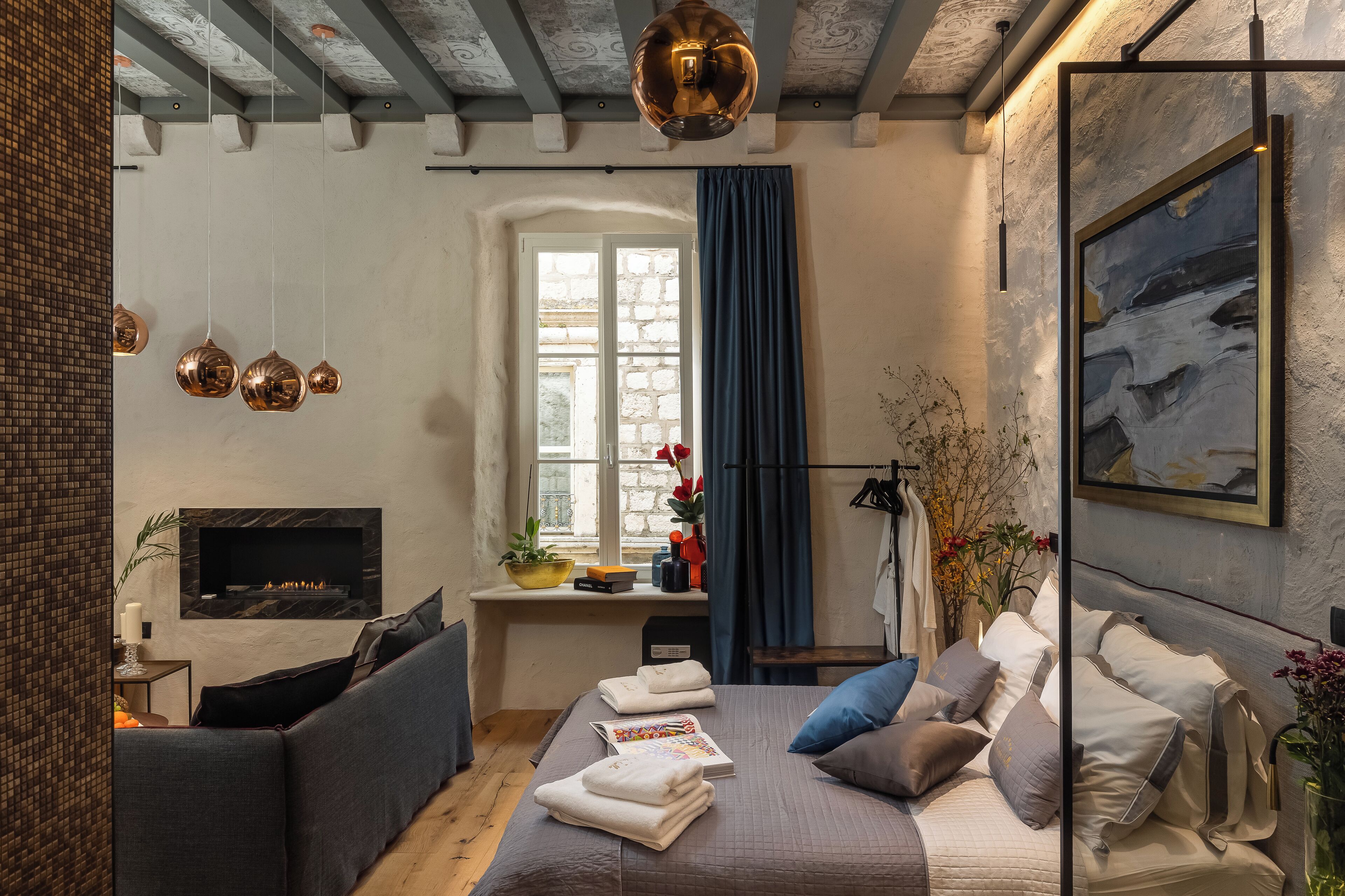 Ein modernes Schlafzimmer mit Kamin, einer Couch, einem Bett mit Kissen und einem Bild an der Wand.