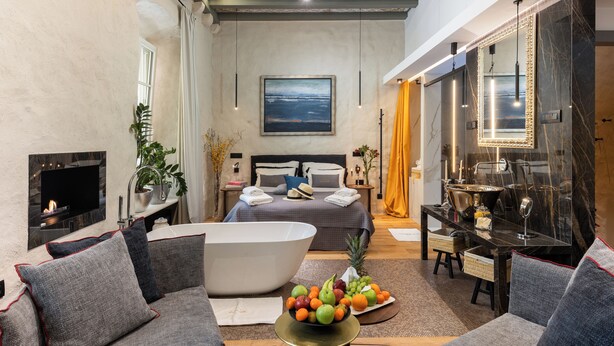 Ein modernes Schlafzimmer mit einem großen Bett, einer Badewanne und einem Essbereich mit Obstschale.