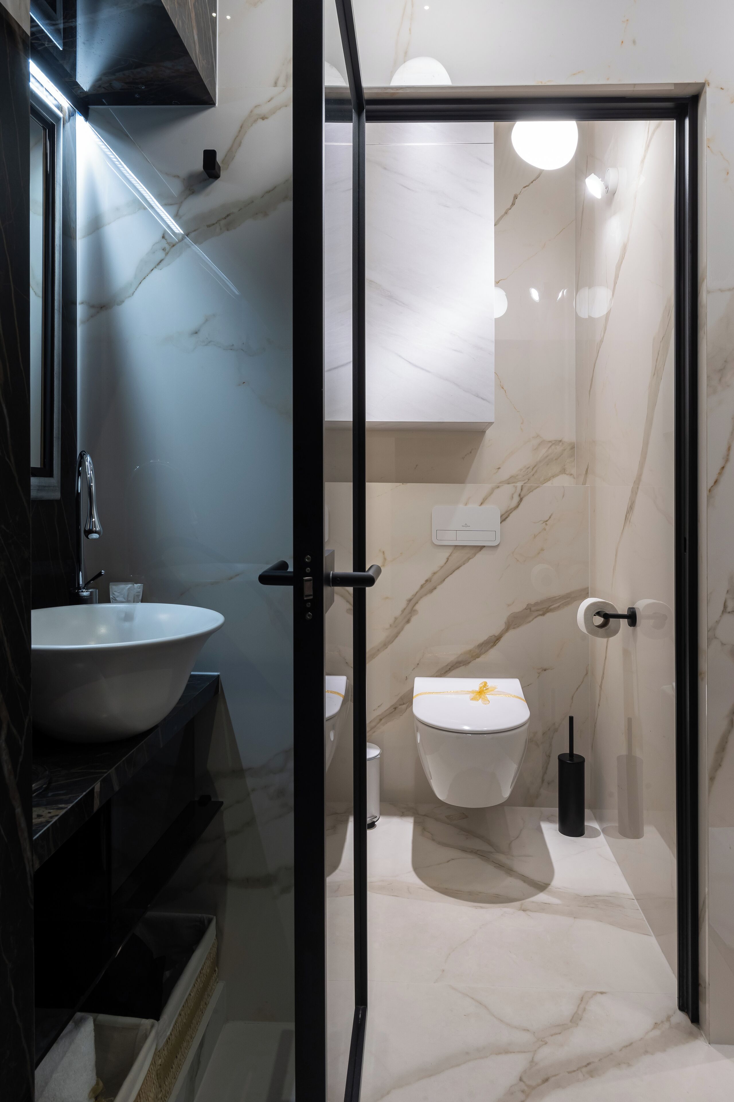 Un baño moderno con lavamanos, inodoro y ducha con cerramiento de vidrio de mármol.