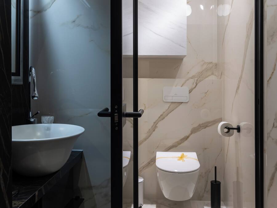 A modern bathroom with a marble sink, toilet, and glass-enclosed shower.