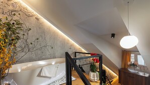 Ein modernes Badezimmer mit einer freistehenden Badewanne, einer Holzbank und einer dekorativen Vase mit Blumen.