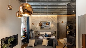 Ein modernes Wohnzimmer mit einer Couch, einem Kamin und einer Essecke mit Tisch für zwei Personen.
