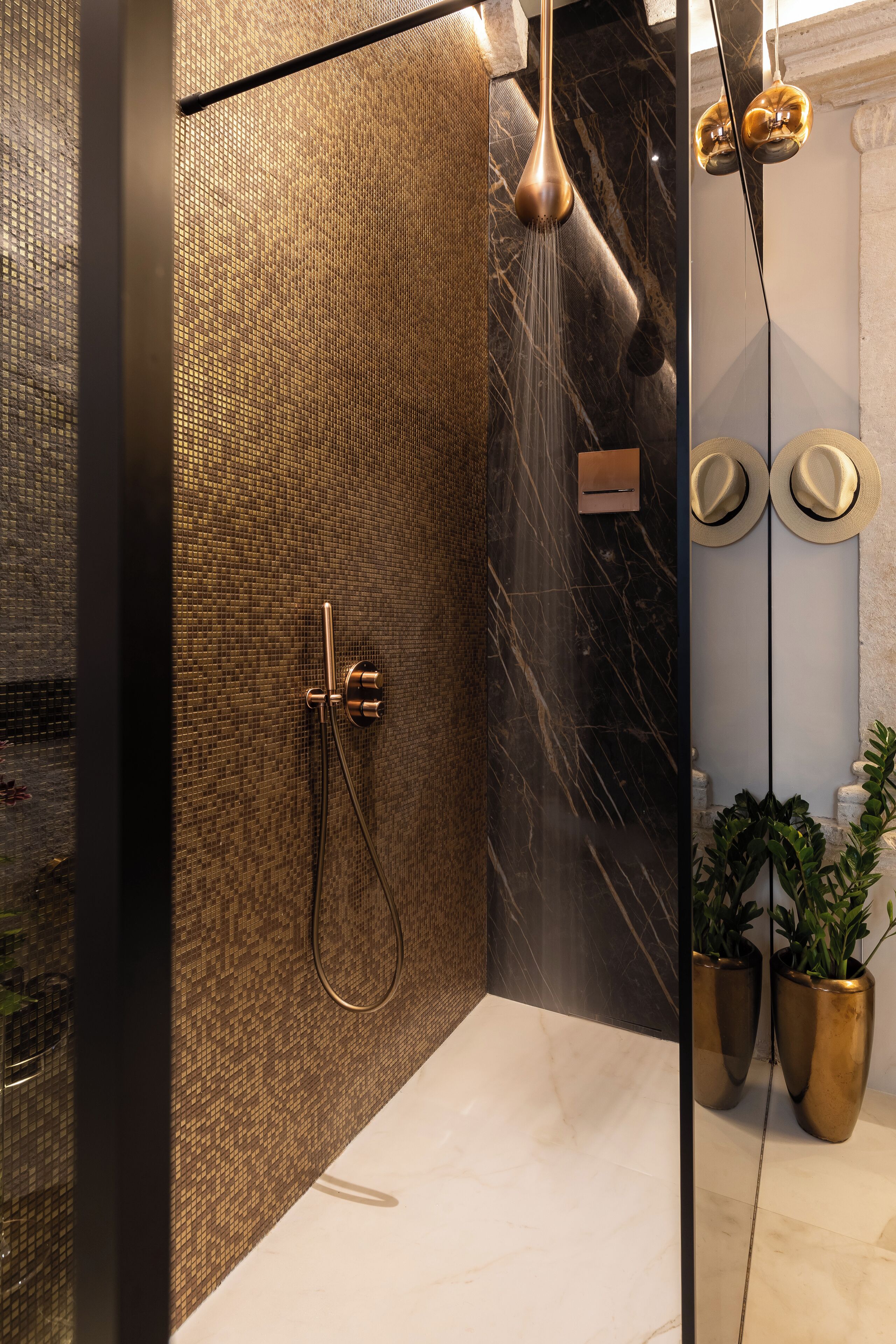 Een moderne badkamer met een douche, een spiegel en twee planten in potten.
