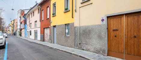 A street with colorful buildings, a no parking sign, and a closed wooden garage door.