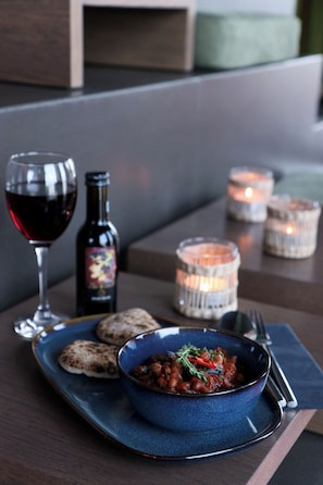 A dining table with a blue bowl of food, a wine glass, a bottle, and candles. - VISIONAPARTMENTS Zurich Brandschenkestrasse (Zürich)