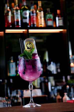 A cocktail in a glass with a mint garnish, set against a background of various liquor bottles. - VISIONAPARTMENTS Zurich Brandschenkestrasse (Zürich)