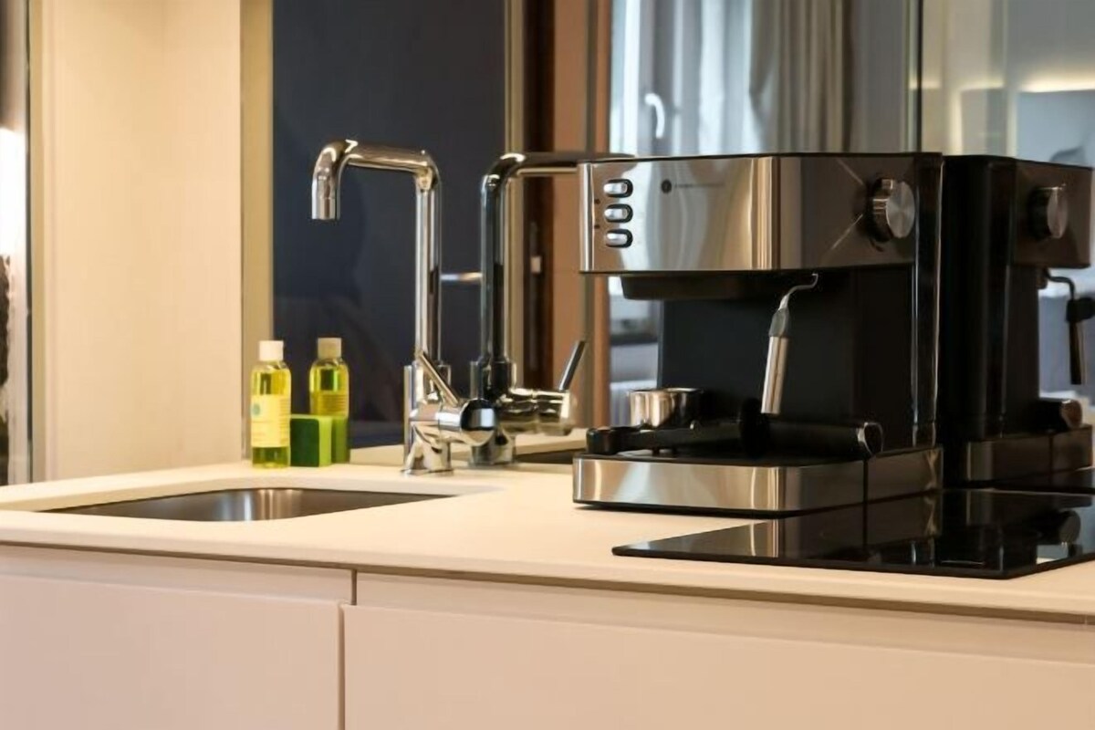 A modern kitchen with a built-in coffee maker, a stainless steel faucet, and two bottles of olive oil on the counter.