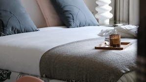 A neatly made bed with a patterned headboard, a vase with flowers, and a tray with a candle on a bedside table. - VISIONAPARTMENTS Zurich Brandschenkestrasse (Zürich)