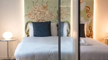 Ein modernes Schlafzimmer mit einem großen Bett, einer Glastrennwand und einem runden Tisch mit einer Lampe.