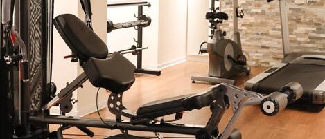 A home gym with exercise equipment, a treadmill, and a TV.