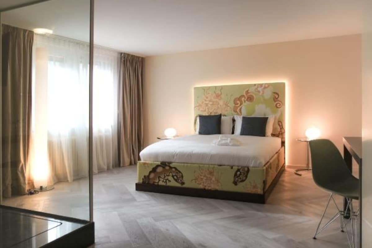 A hotel room with a large bed, a desk, and a chair.