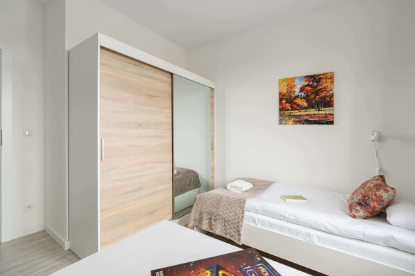 A modern bedroom with a bed, a wardrobe, a painting, and a bedside table. - Two Bedroom Apartment | Balcony | Parking. (Poznan)